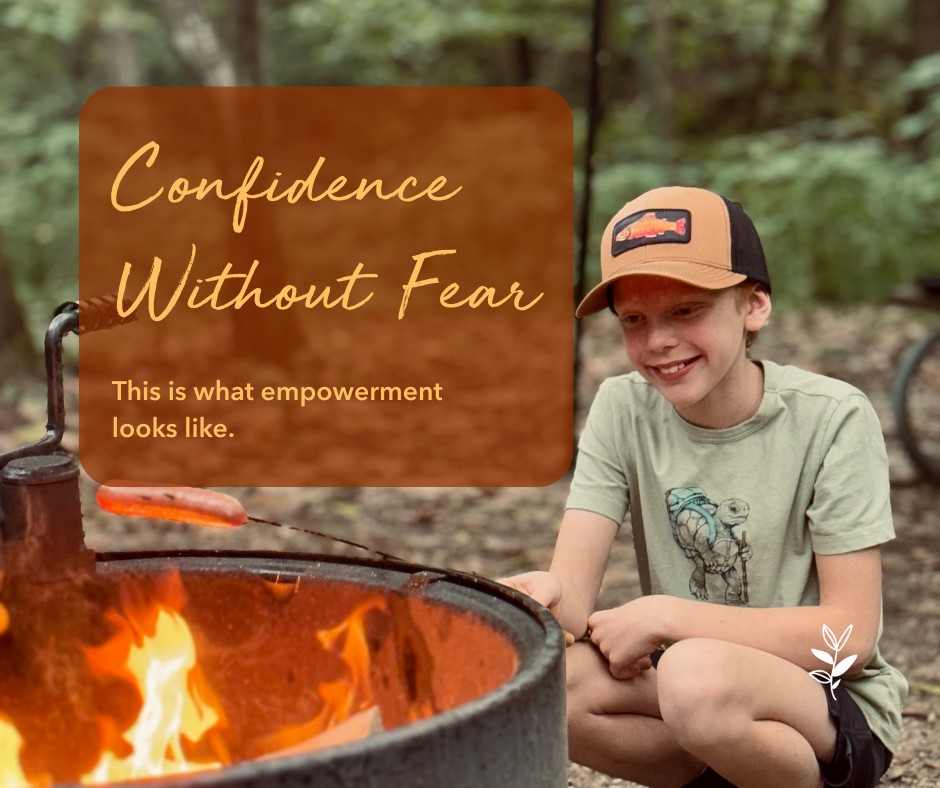 A young boy smiling while sitting near a campfire, with text overlay reading 'Confidence Without Fear' and 'This is what empowerment looks like'.